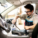 A Man at work cleaning automobile at car wash